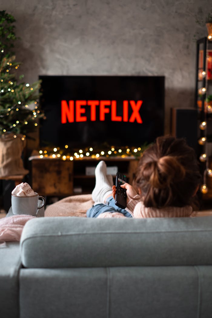 creative-02 Woman relaxing on sofa with hot chocolate and Netflix on a winter evening.