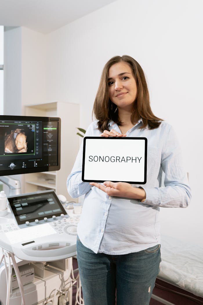 digital-01 Pregnant woman holding a tablet displaying 'Sonography' in a medical clinic setting.